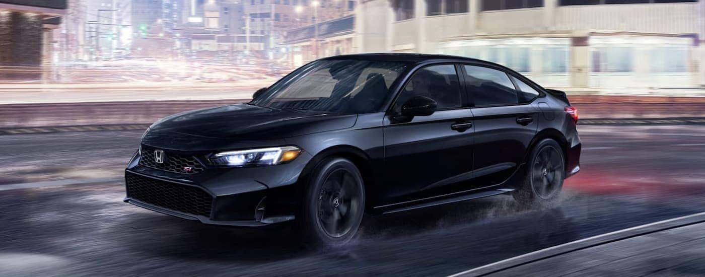 A black 2026 Honda Civic SI driving in a city at night