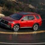 Red 2026 Honda Pilot driving down the road