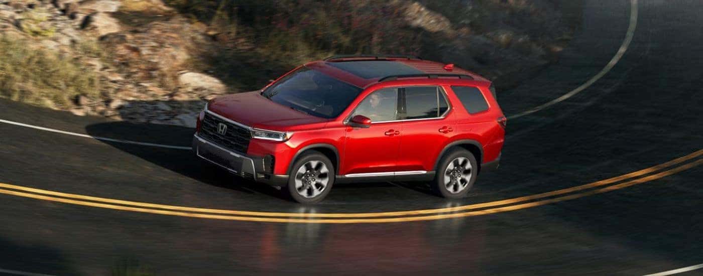 Red 2026 Honda Pilot driving down the road