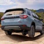 A gray pearl 2026 Honda Pilot shown driving on a sandy road.