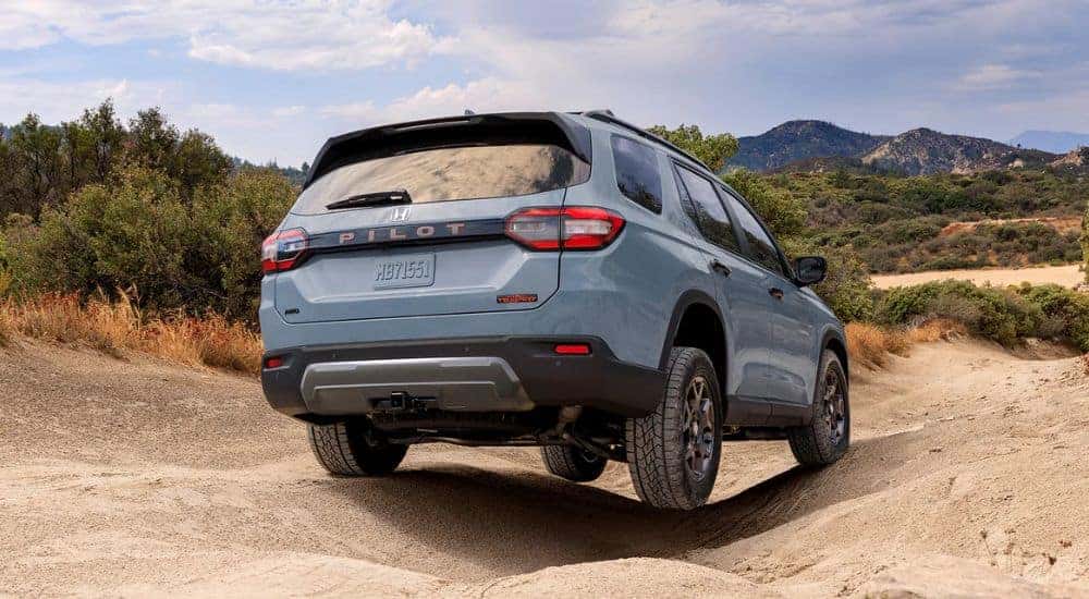 A gray pearl 2026 Honda Pilot shown driving on a sandy road.