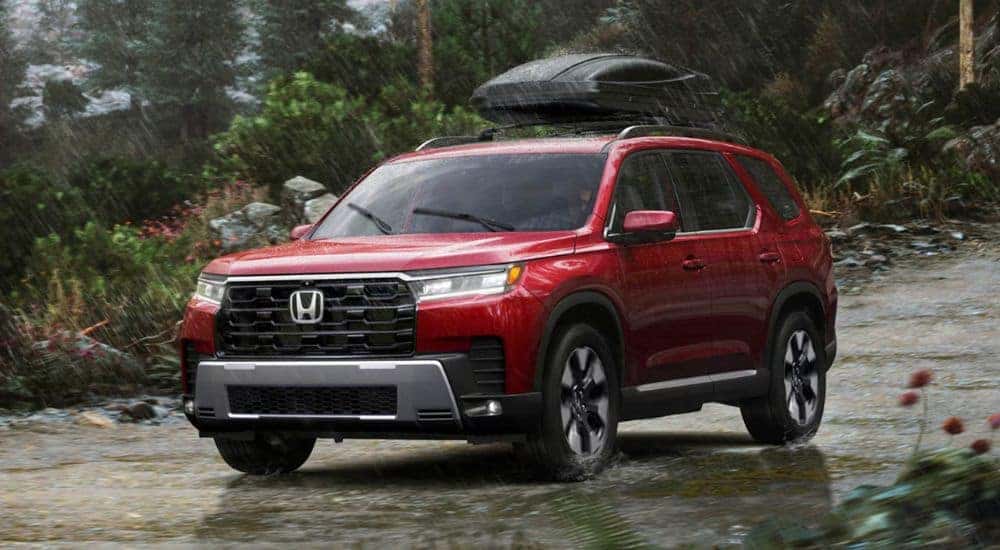 A red 2026 Honda Pilot Elite shown driving in the rain.