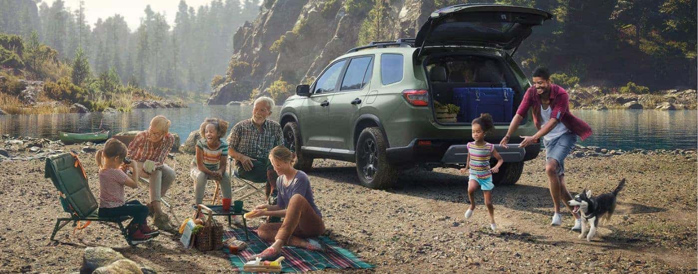 Green 2026 Honda Pilot parked in front of a lake with a family.