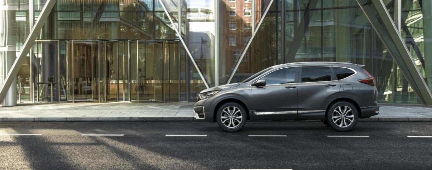 A gray 2022 Honda CR-V Hybrid Touring parked in front of a glass building.