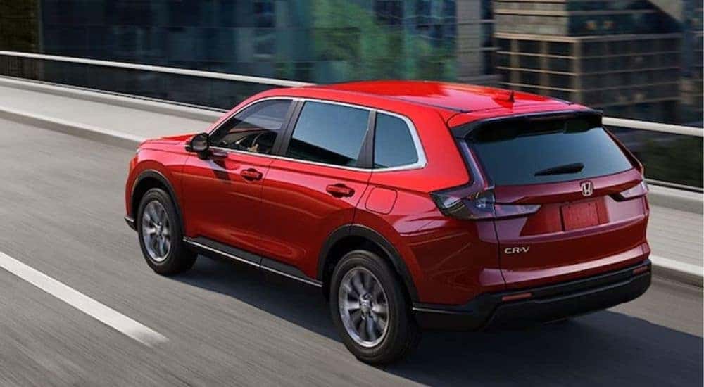 A red 2026 CR-V EX shown driving over a city bridge.