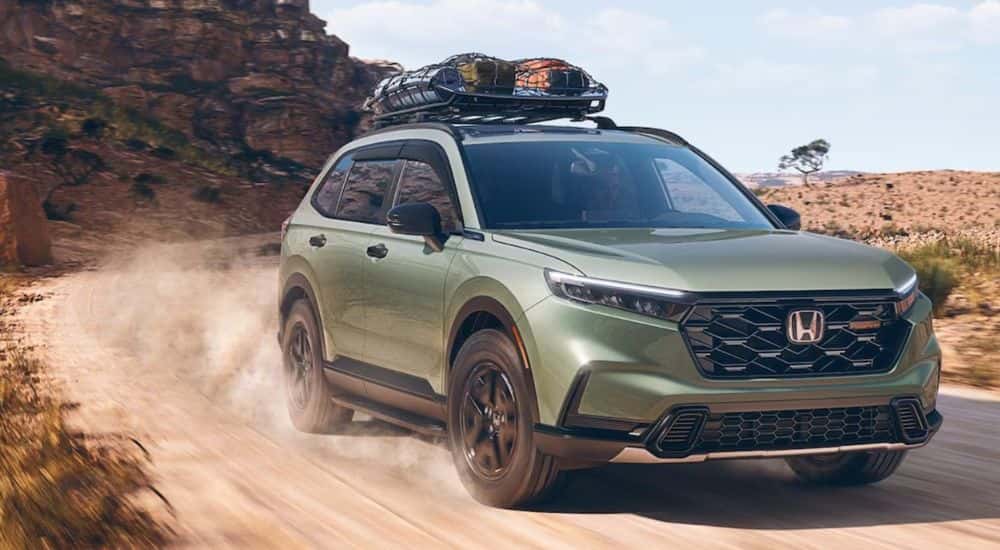 A green 2026 Honda CR-V TrailSport shown driving a dirt road.