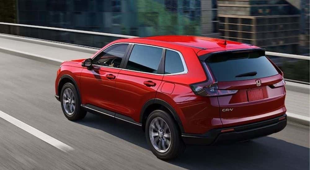 A red 2026 CR-V EX shown driving over a city bridge.