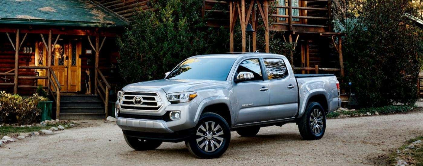 A silver 2023 Toyota Tacoma is shown parked near a log cabin after viewing a Toyota Tacoma for sale near Smyrna.