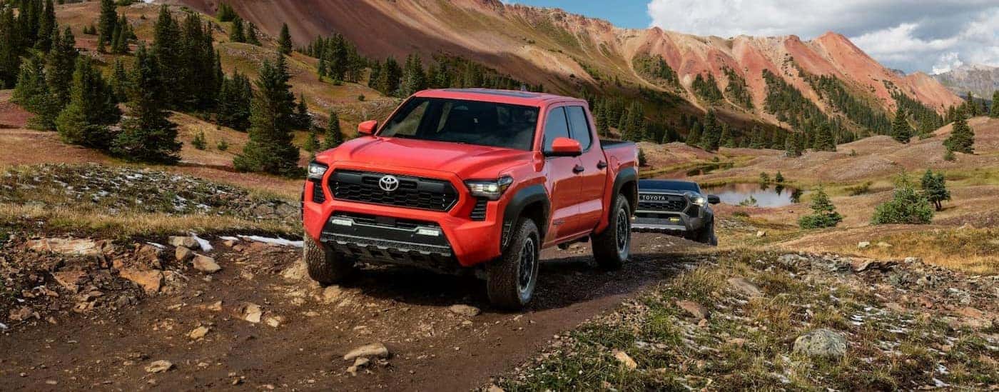 A red 2024 Toyota Tacoma TRD-Offroad is shown driving near a mountain.