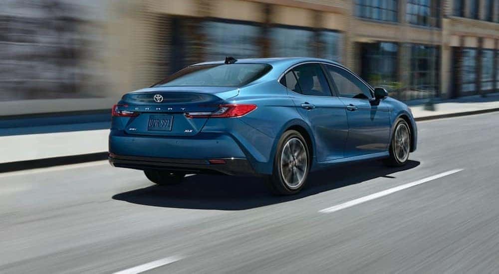 A blue 2025 Toyota Camry XLE is shown driving on a city street.