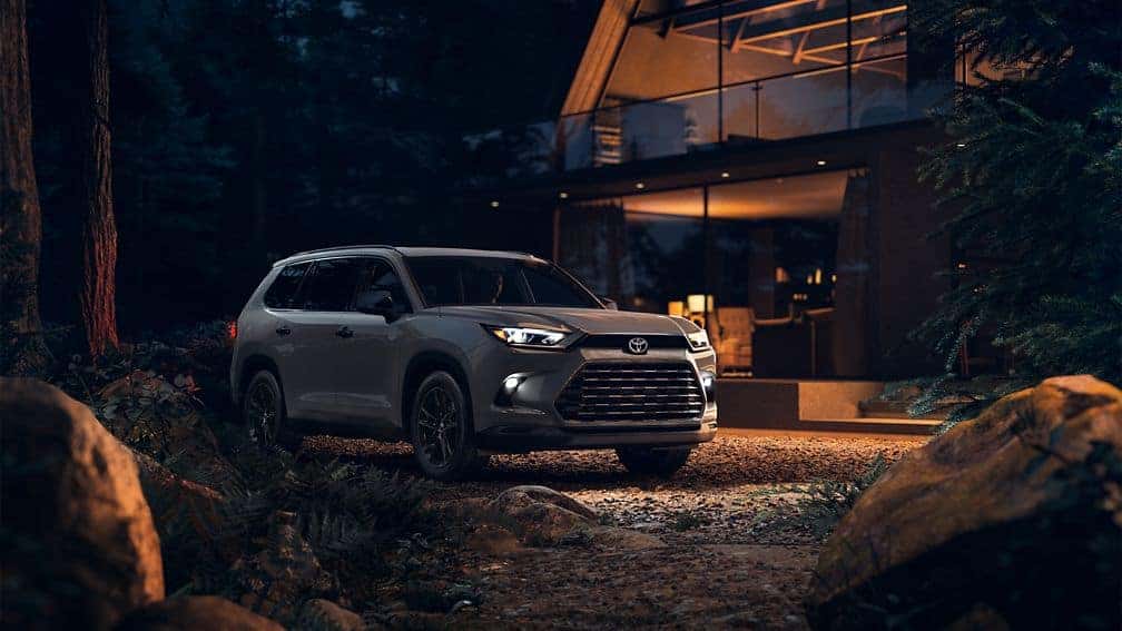 A gray 2025 Toyota Grand Highlander parked outside of a cabin in the woods