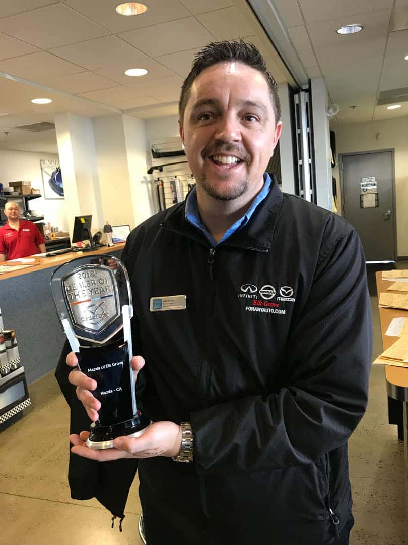 Mazda Elk Grove employee holding Dealer of The Year award