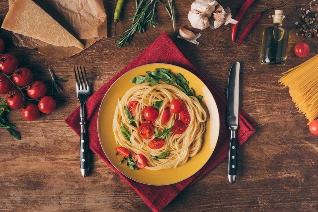 Italian pasta dish on a plate surrounded by ingredients