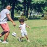 Father and son playing soccer together at a local park
