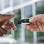 Person handing a Mercedes-Benz key fob to another hand
