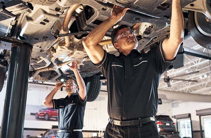 Mercedes-Benz service technicians working underneath a vehicle