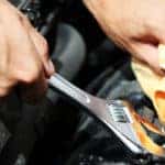 Hands with wrench and cloth working on engine