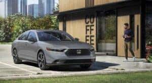 A gray 2024 Honda Accord Sport is shown parked near a coffee shop.