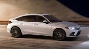 A white 2024 Honda Civic Hatchback is shown driving to a Honda dealer near Grapevine.