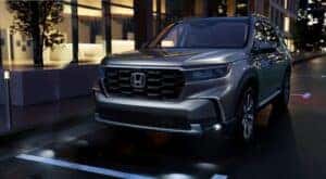 A silver 2023 Honda Pilot for sale near Grapevine is shown parked on a city street.