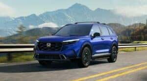 A blue 2024 Honda CR-V Sport Touring Hybrid is shown driving to visit a Honda dealer near Watauga.