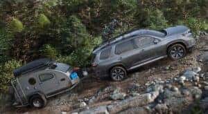 A gray 2024 Honda Pilot is shown driving uphill on off-road terrain.