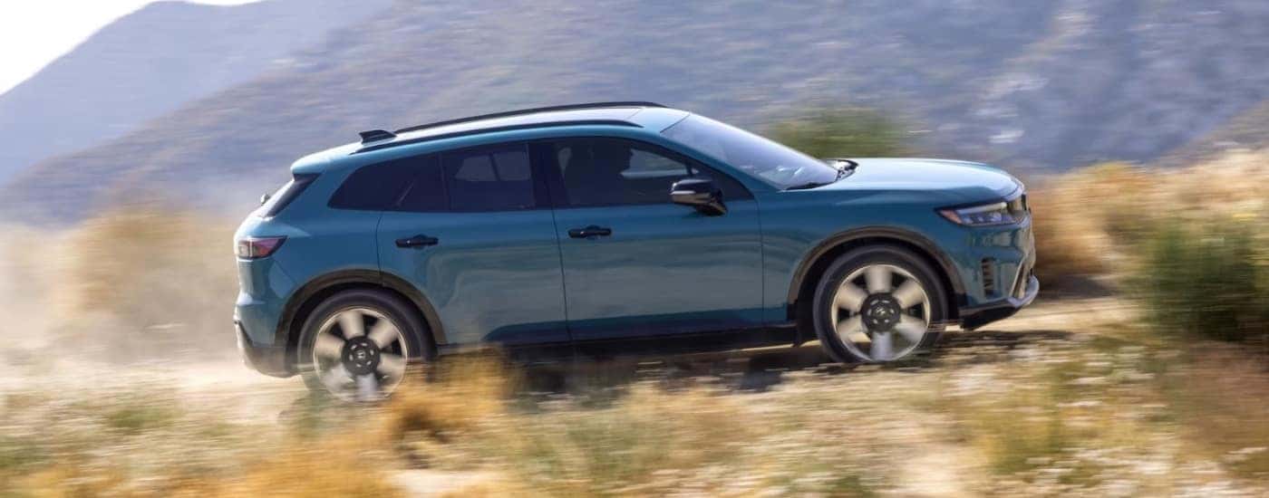 A grey 2024 Honda Prologue Elite is shown from the side driving on an open road.