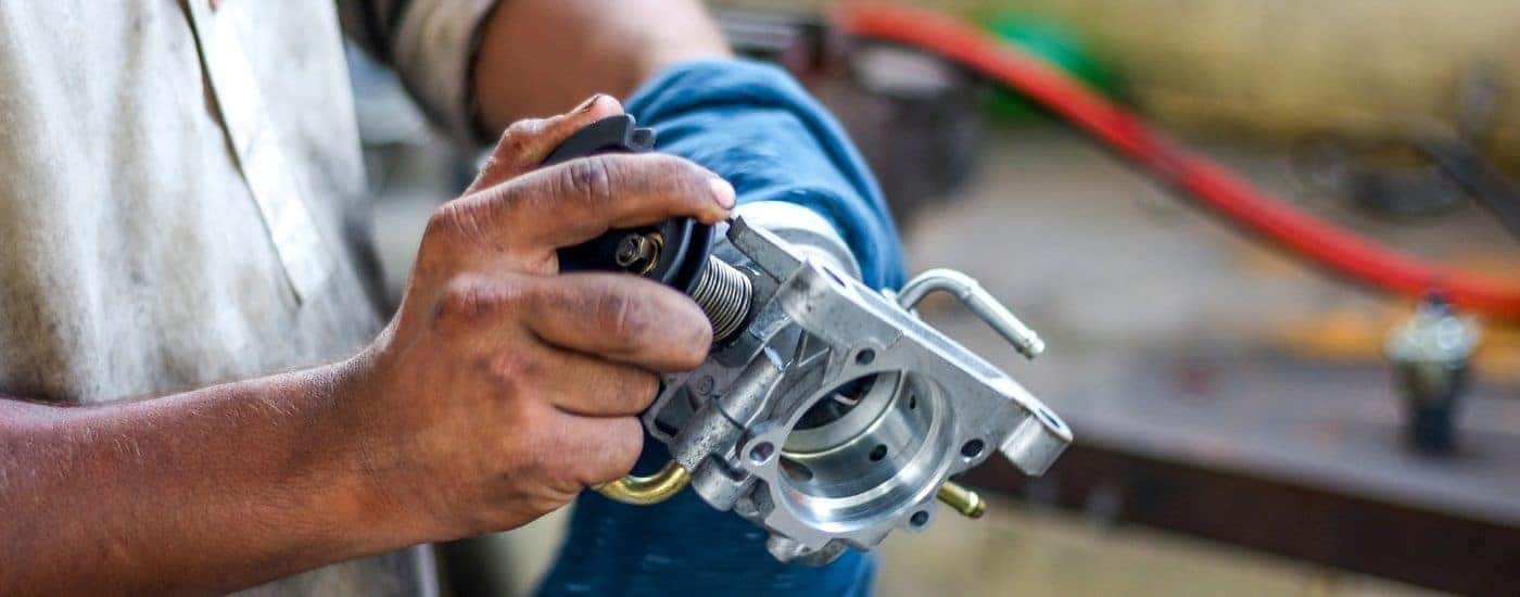 Close-up of a mechanic cleaning a throttle body.