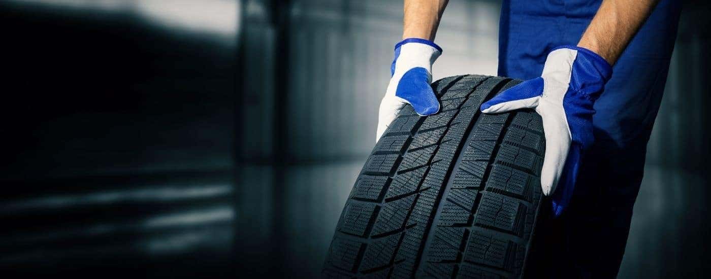 Close-up of a mechanic with blue gloves moving a new tire.