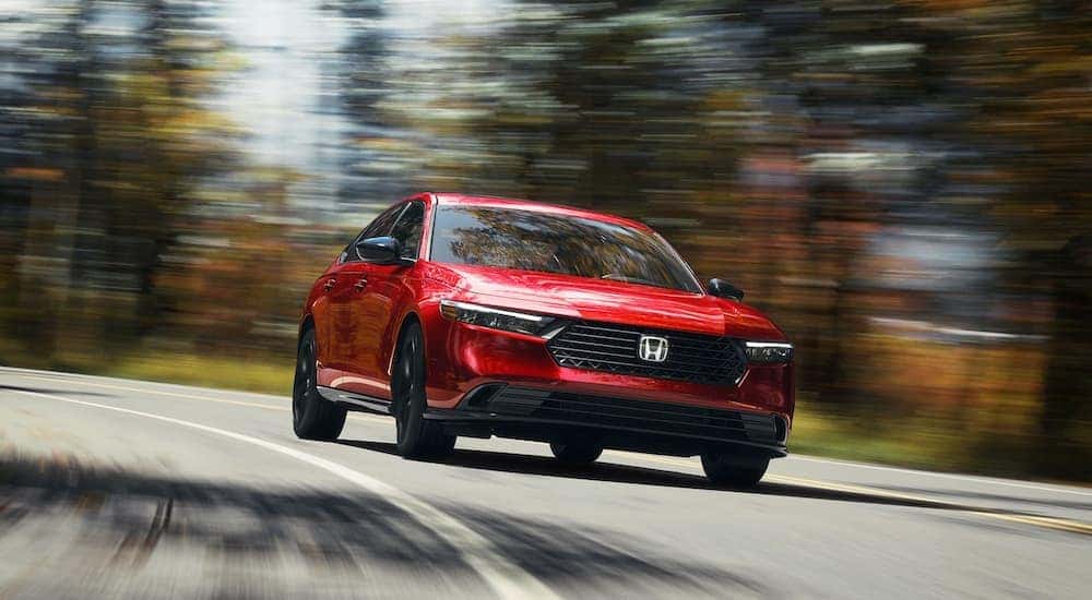 A red 2025 Honda Accord Sport L Hybrid driving from a dealer with a Honda Accord Hybrid for sale.