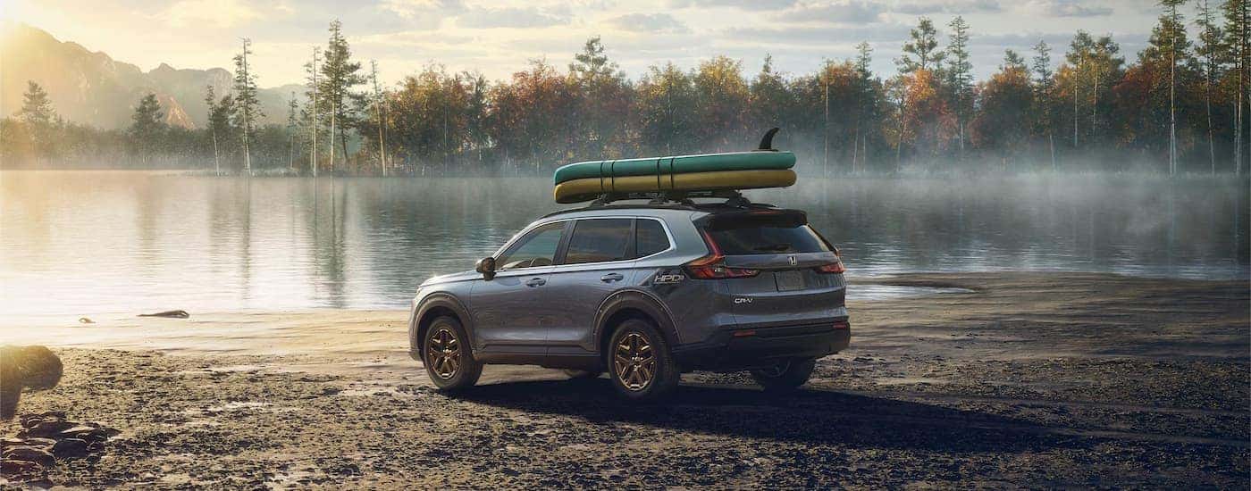 Grey 2025 Honda CR-V Hybrid parked next to a lake.