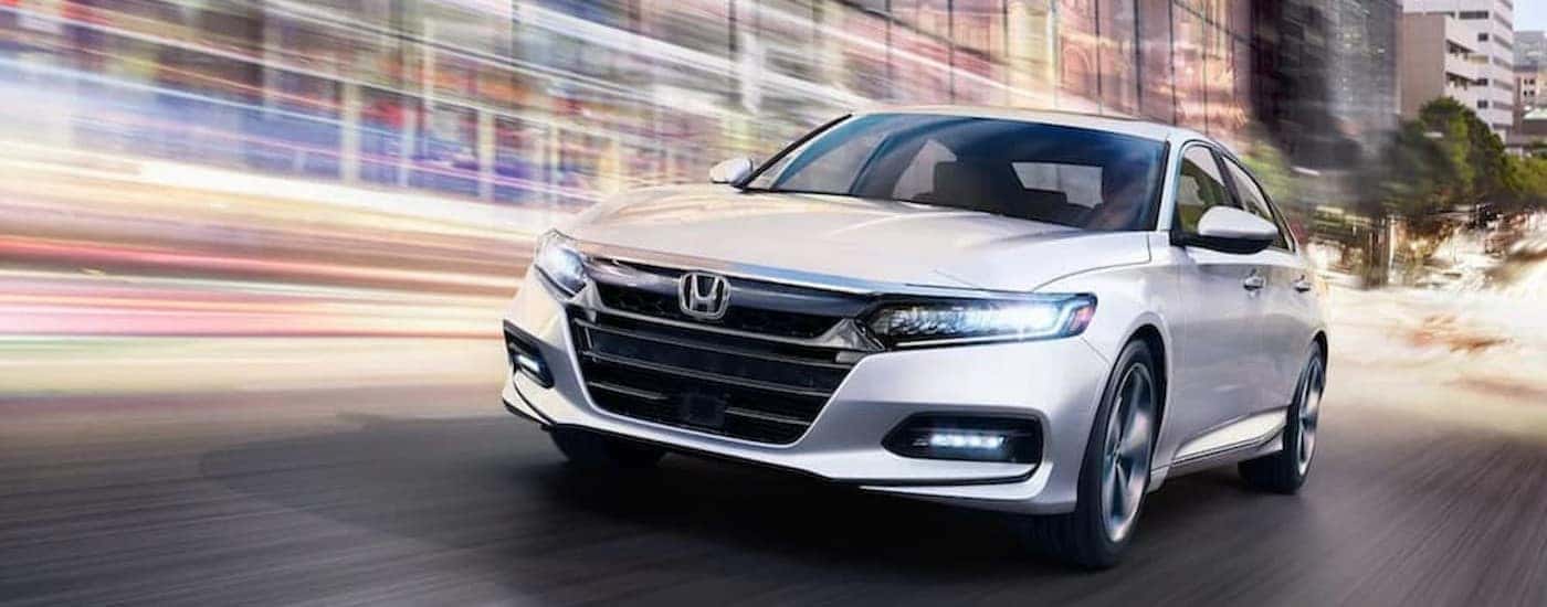 A white 2018 Honda Accord Touring is shown driving fast on a city street.