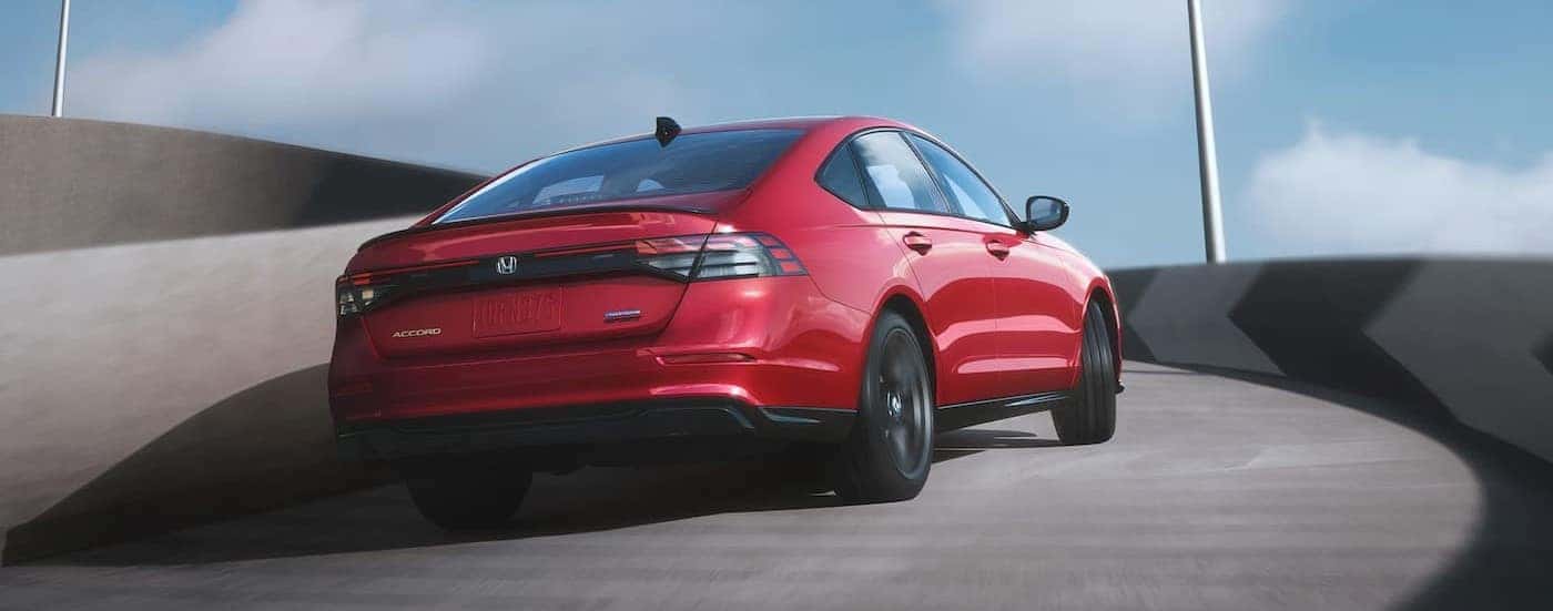 A red 2025 Honda Accord Hybrid is shown driving up a ramp.
