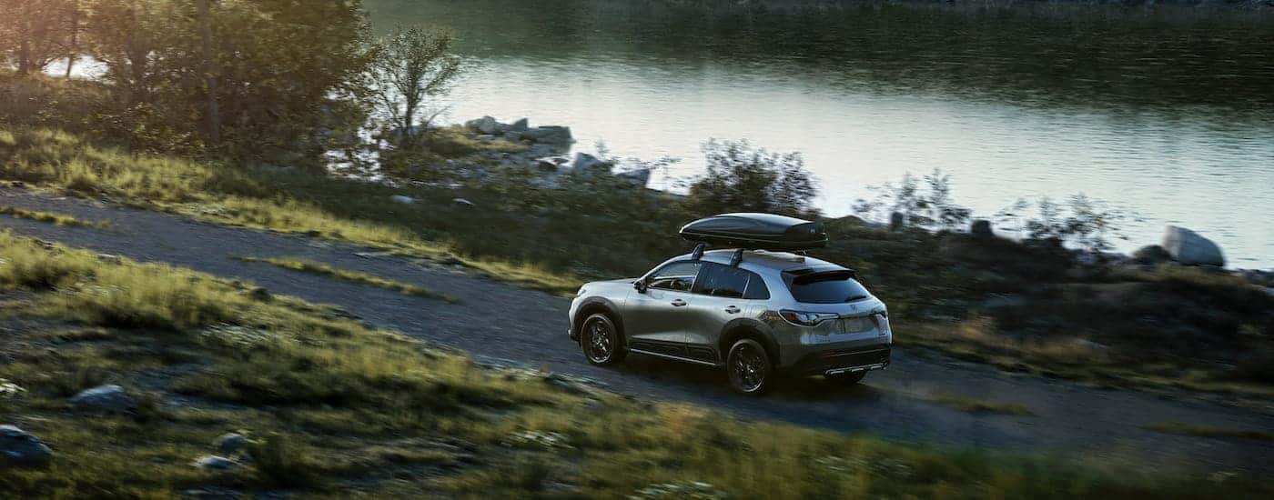 High rear angle view of a grey 2025 Honda HR-V Sport driving through wilderness from a dealer with a Honda HR-V for sale near Irving.