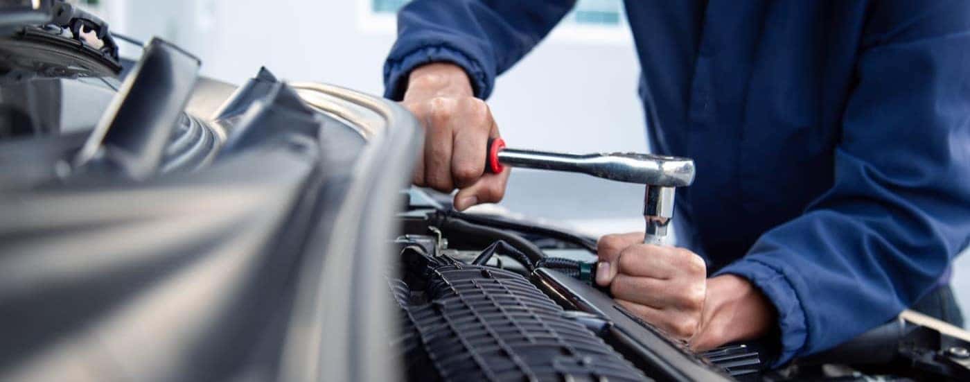 A technician is shown working on a vehicle's engine.
