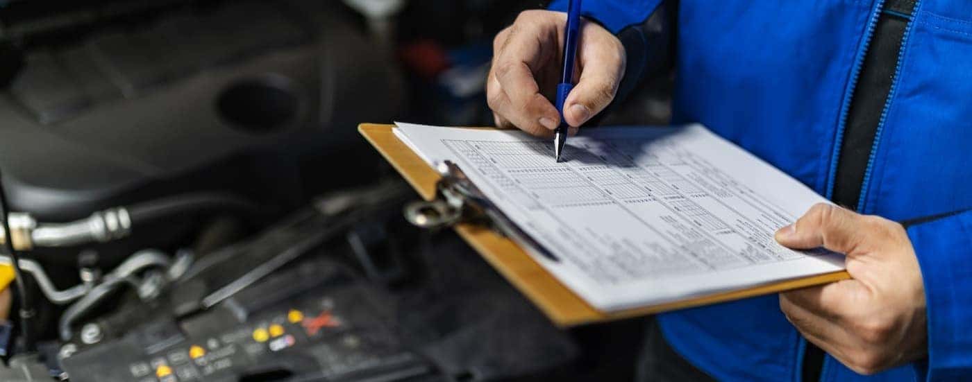 A technician is shown writing on a clipboard at a Honda service center near Keller.