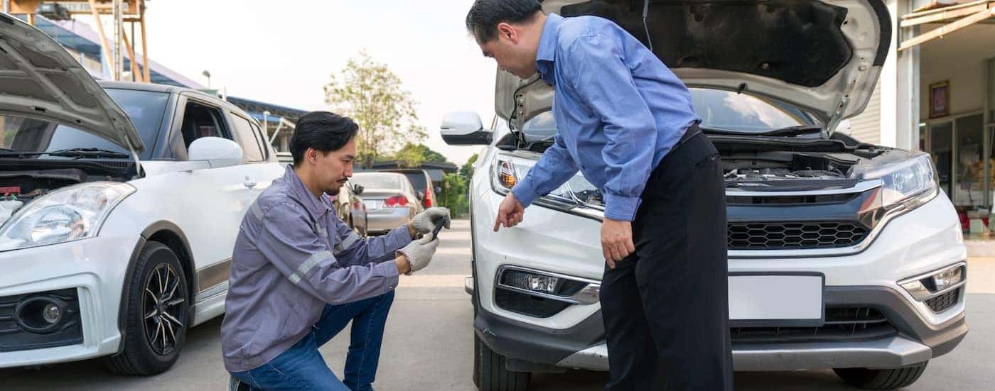 Two employees are evaluating a vehicle's damage.
