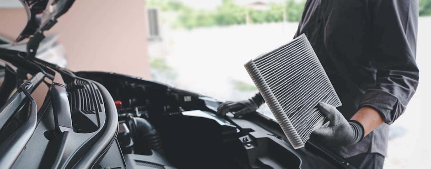 A mechanic replacing an air filter in a car engine.