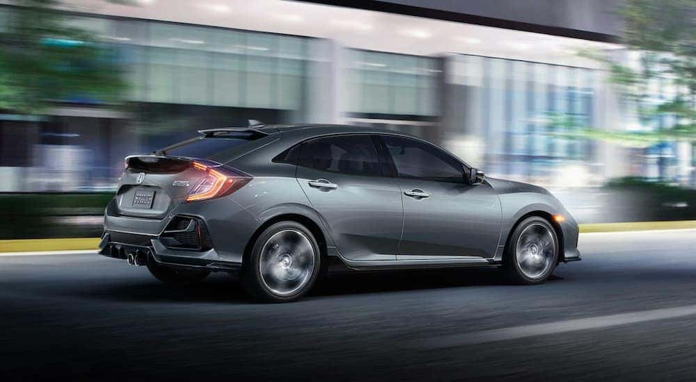 A gray 2021 Honda Civic Hatchback driving in a city.