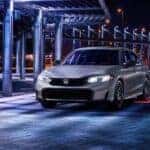 A gray 2025 Honda Civic Sport driving at night.