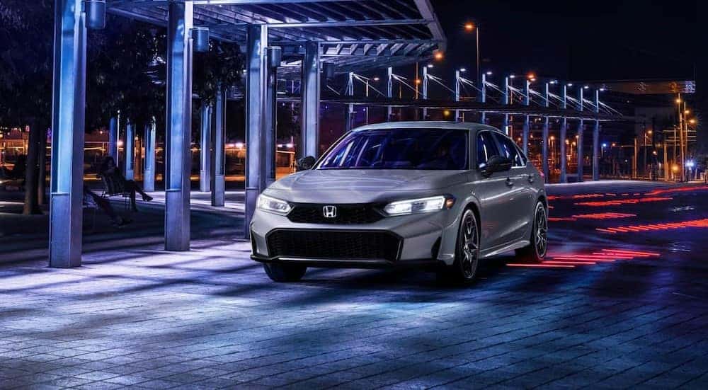 A gray 2025 Honda Civic Sport driving at night.