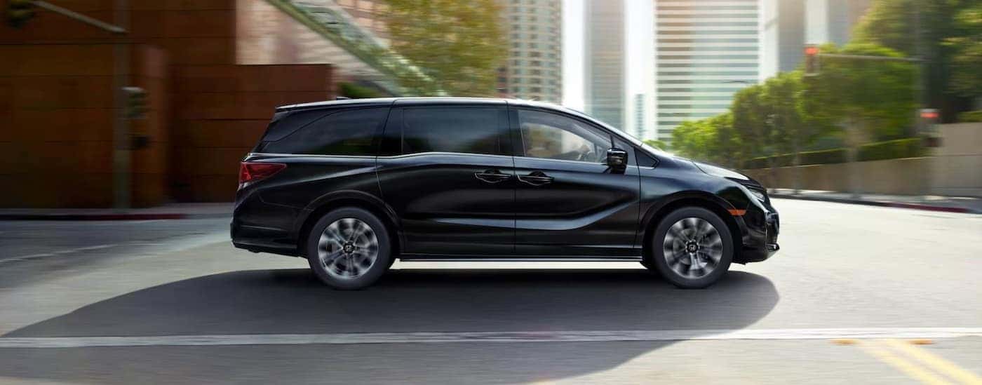 A black 2025 Honda Odyssey for sale driving in a city.