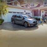 A silver 2025 Honda Odyssey for sale parked near a family.