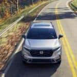 A silver 2026 Honda CR-V Sport Touring Hybrid driving on a highway.
