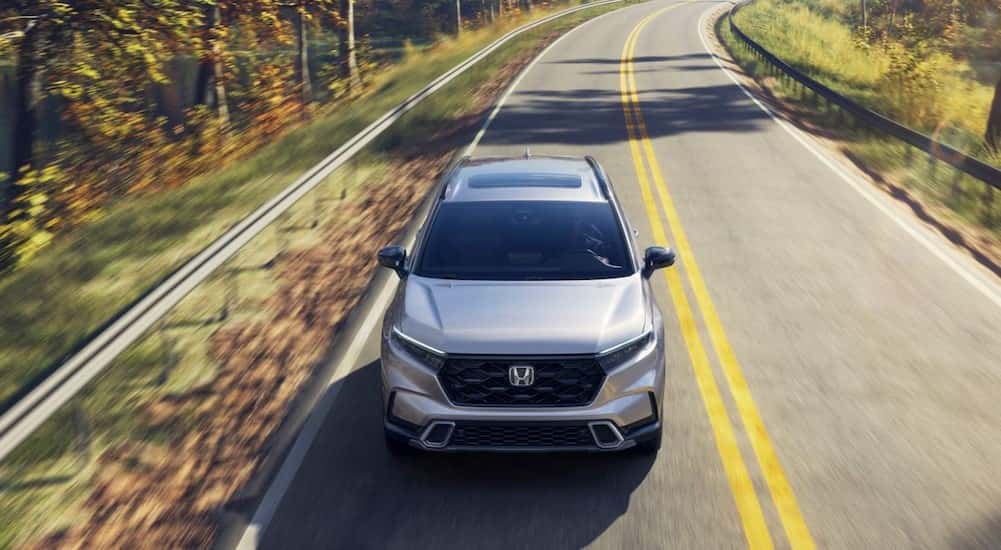 A silver 2026 Honda CR-V Sport Touring Hybrid driving on a highway.