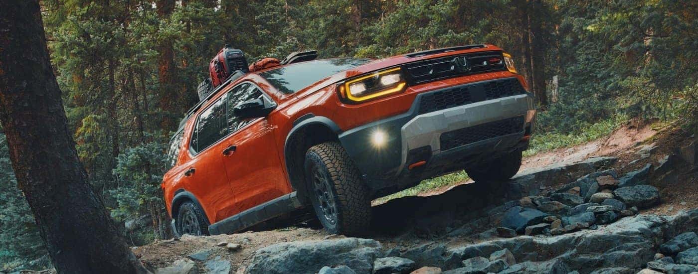 An orange 2026 Honda Passport TrailSport Elite on an off-road trail