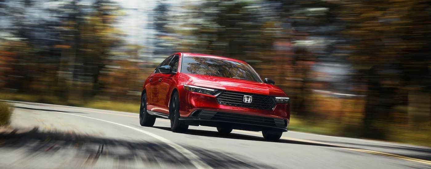 A red 2025 Honda Accord Sport-L Hybrid driving around a bend.