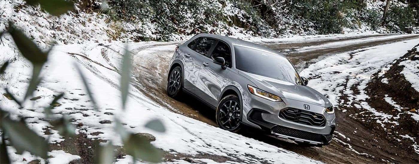 A silver 2023 Honda HR-V driving in snowy conditions.