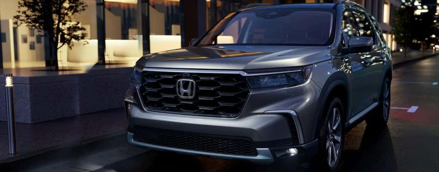 A silver 2023 Honda Pilot for sale near Grapevine is shown parked on a city street.
