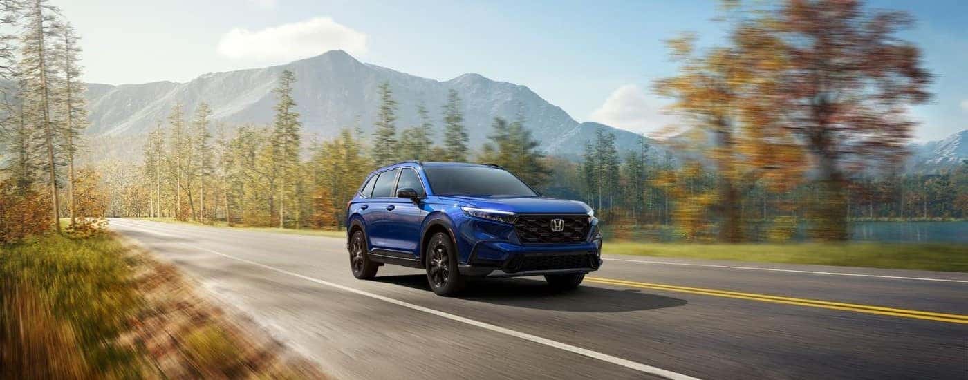 A blue 2024 Honda CR-V for sale near Keller driving down a road.